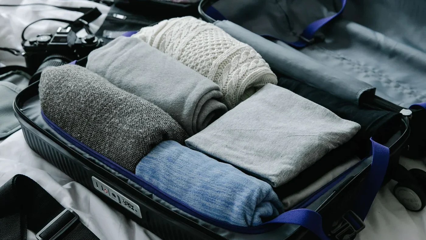 Mala aberta sobre uma cama com roupas dobradas organizadas para a viagem