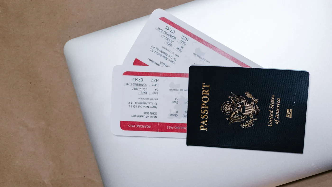 Passaporte e cartões de embarque apoiados sobre um notebook, em cima de uma mesa
