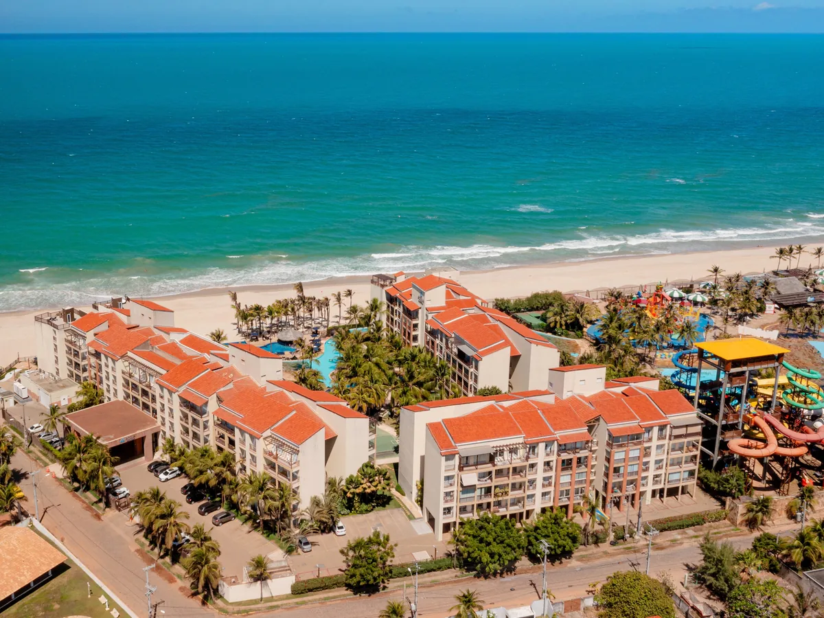 Vista aérea do Acqua Beach Park, com os prédios de telhado laranja, a praia e os toboáguas do Aqua Park ao lado