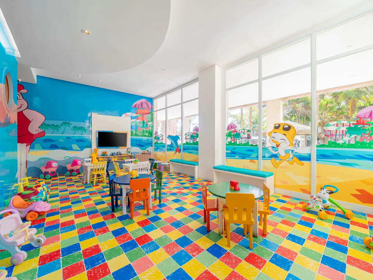 Kid's Club do Acqua Beach Park, com mesas infantis, piso colorido e janelas para o jardim