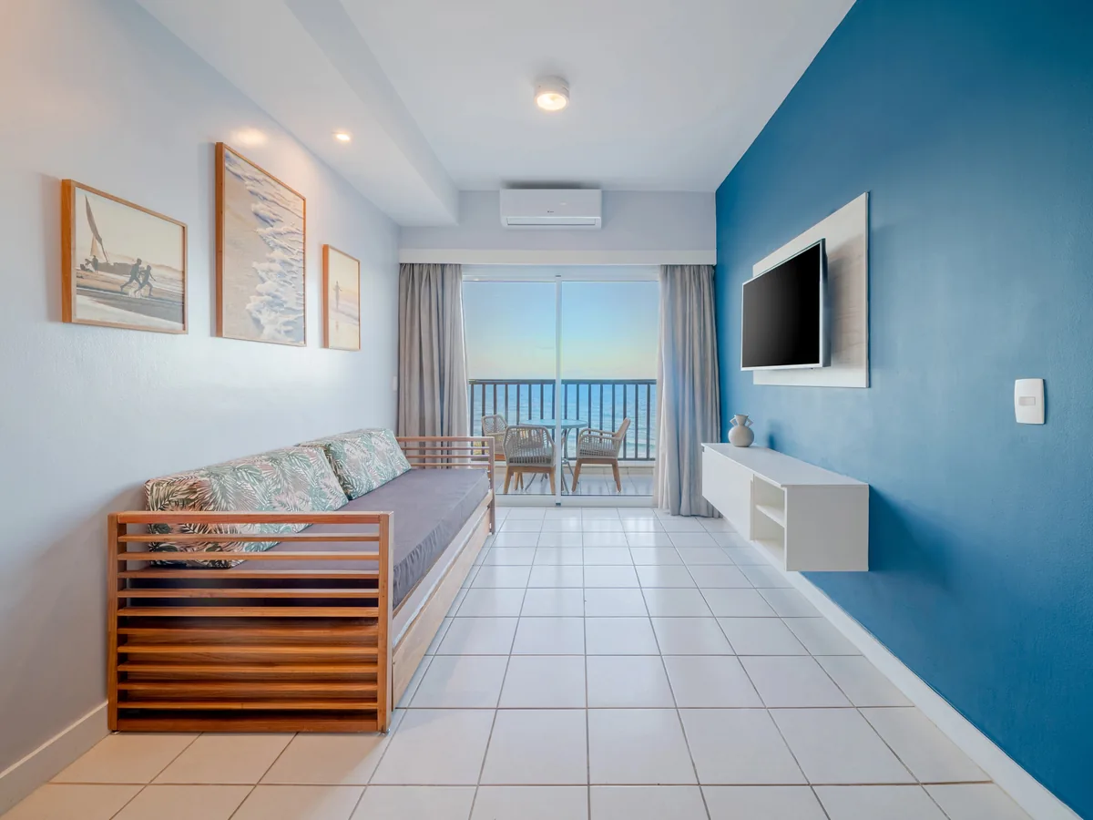 Sala de uma suíte do Acqua Beach Park, com sofá-cama e varanda de frente para o mar