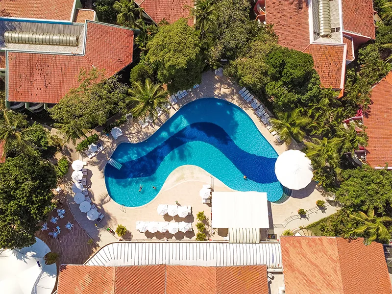 Vista aérea da Piscina Gigante do Resort Arcobaleno, em curva, entre os blocos de telhado vermelho