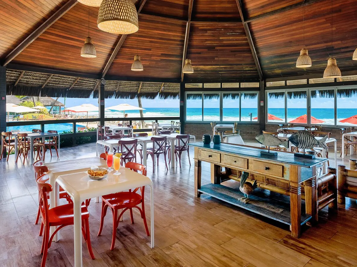 Bar da Praia do Armação Resort, com mesas, teto de madeira e vista para o mar
