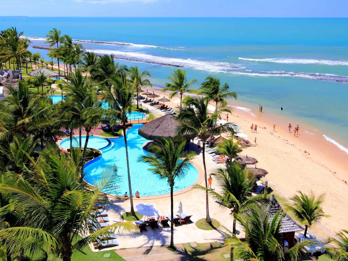 Piscinas do Arraial d'Ajuda Eco Resort entre coqueiros, com a praia e o mar ao lado