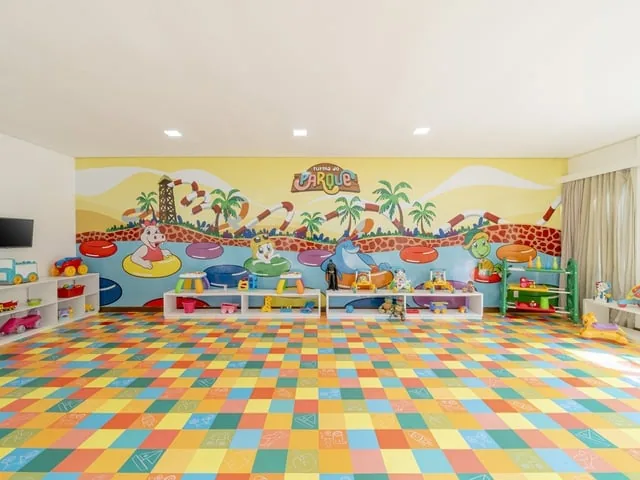 Brinquedoteca do Suites Beach Park, com piso colorido, brinquedos e parede pintada