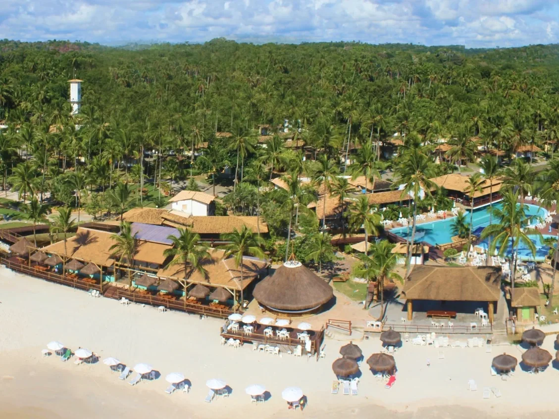 Vista aérea do Cana Brava Resort entre o coqueiral e a praia, com os restaurantes de palha e as piscinas