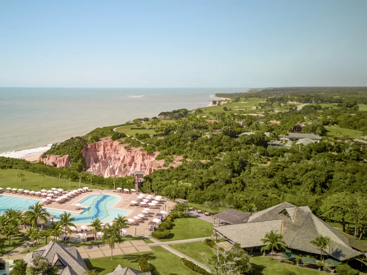 Vista aérea do Club Med Trancoso no alto da falésia, com a piscina, a praia embaixo e o litoral ao fundo
