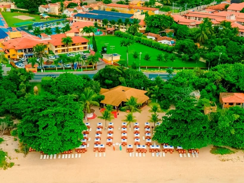 Vista aérea do Coroa Vermelha Beach, com os blocos de telhado laranja, os jardins e o clube de praia na areia