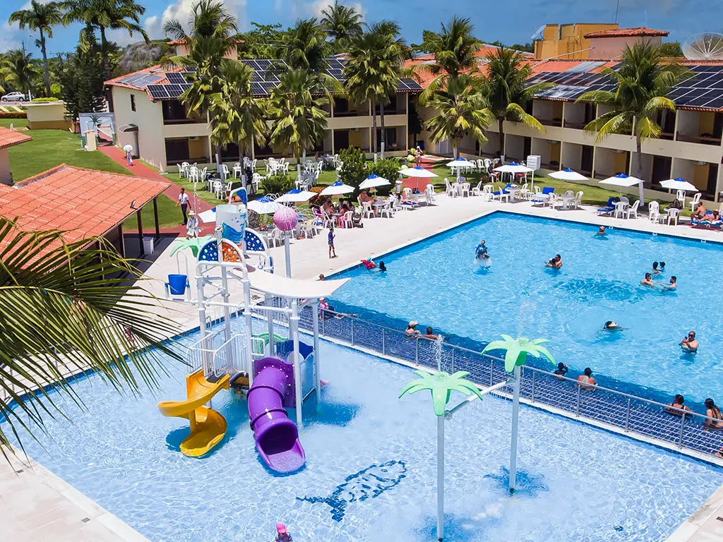 Piscinas do Coroa Vermelha Beach vistas do alto, com brinquedo aquático, hóspedes na água e os blocos de telhado laranja