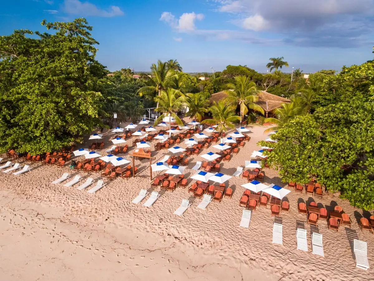 Guarda-sóis, mesas e espreguiçadeiras do Beach Club do Coroa Vermelha Beach na areia, vistos do alto