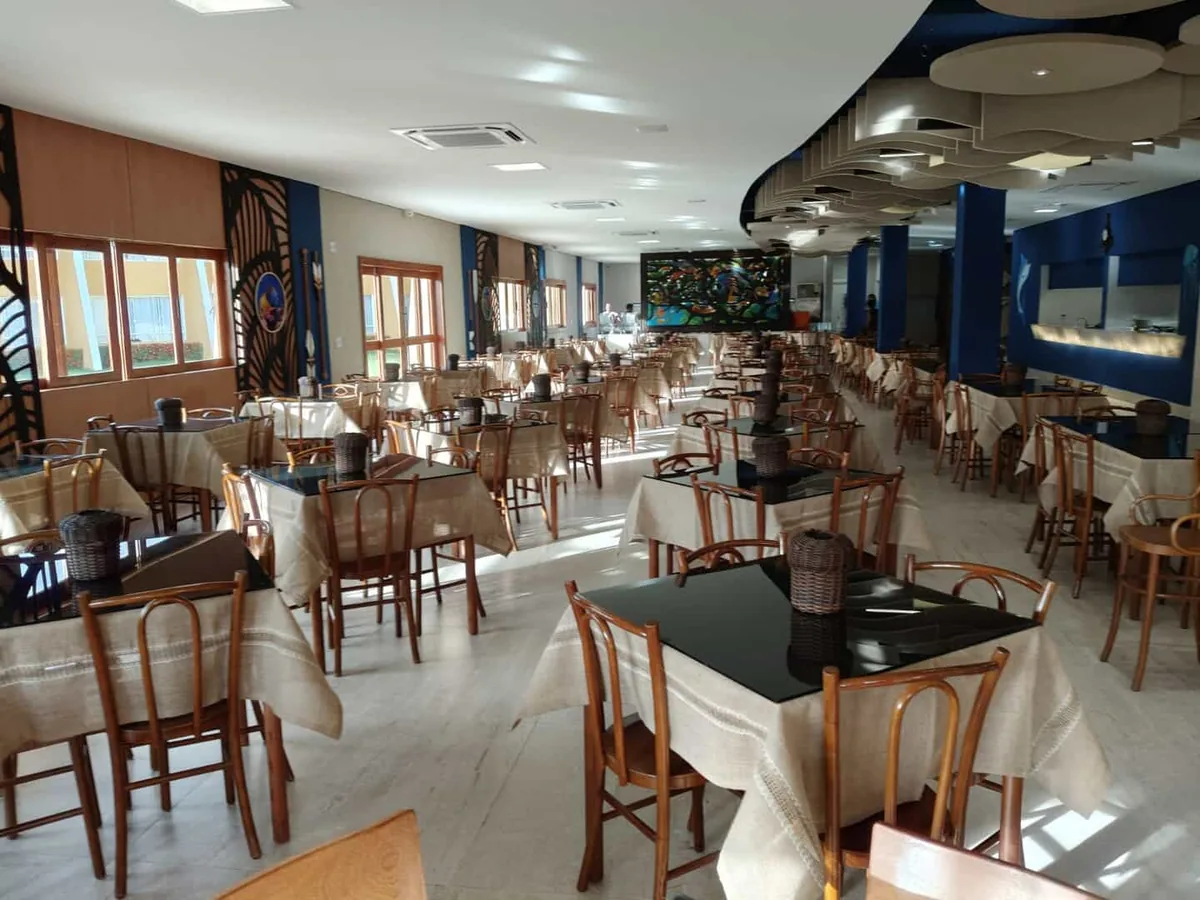 Salão do restaurante do Coroa Vermelha Beach, com mesas postas e janelas para o jardim