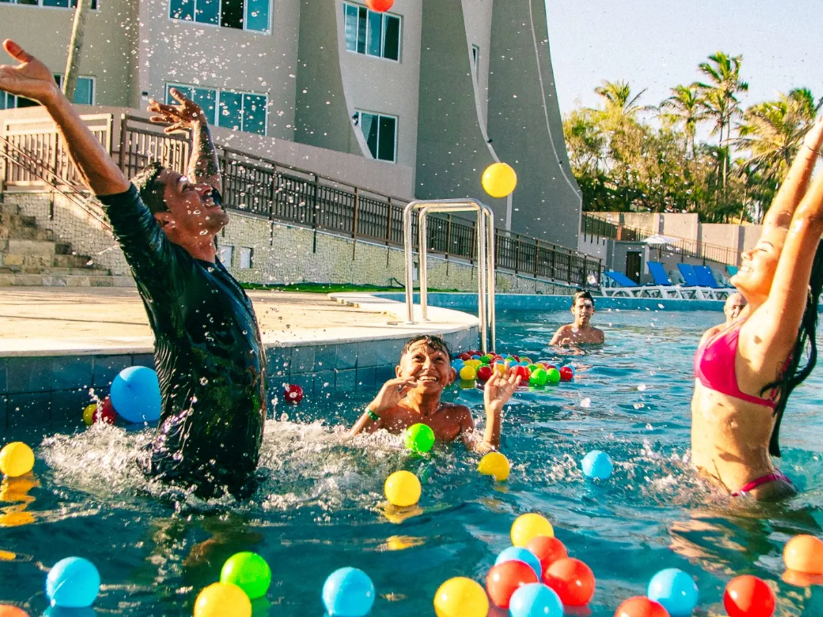 Monitor e hóspedes brincando com bolas coloridas na piscina do Costeira Palace