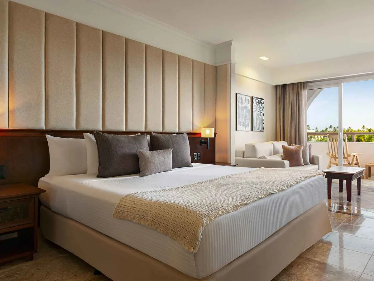 Junior Suite Garden View do Grand Palladium Imbassaí, com cama king, sofá e a porta aberta para a varanda