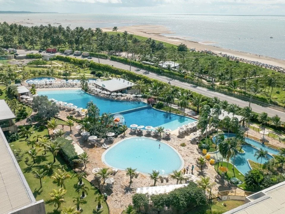 Vista aérea das piscinas do Japaratinga Lounge Resort, com a rodovia, os coqueiros e a praia ao fundo