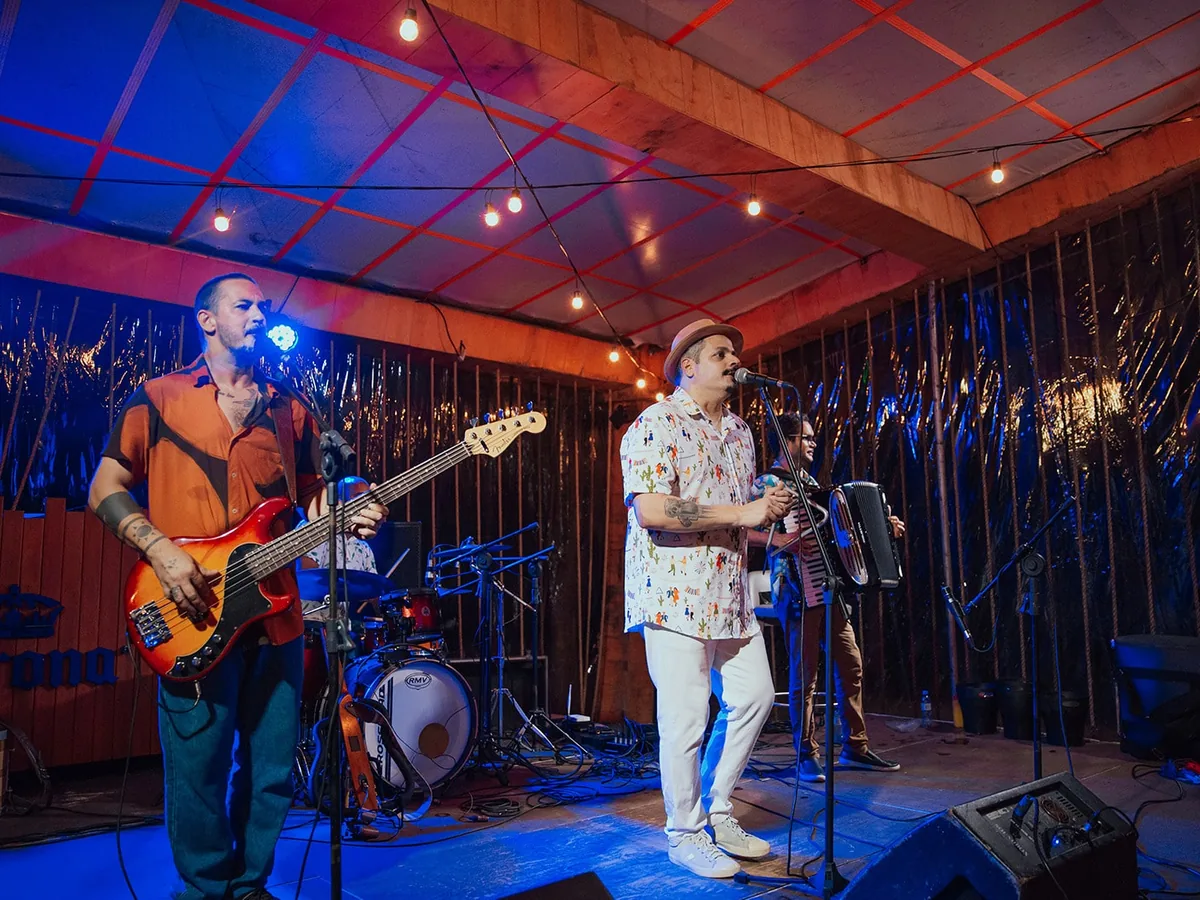 Banda tocando ao vivo num palco iluminado, à noite, no Japaratinga Lounge Resort