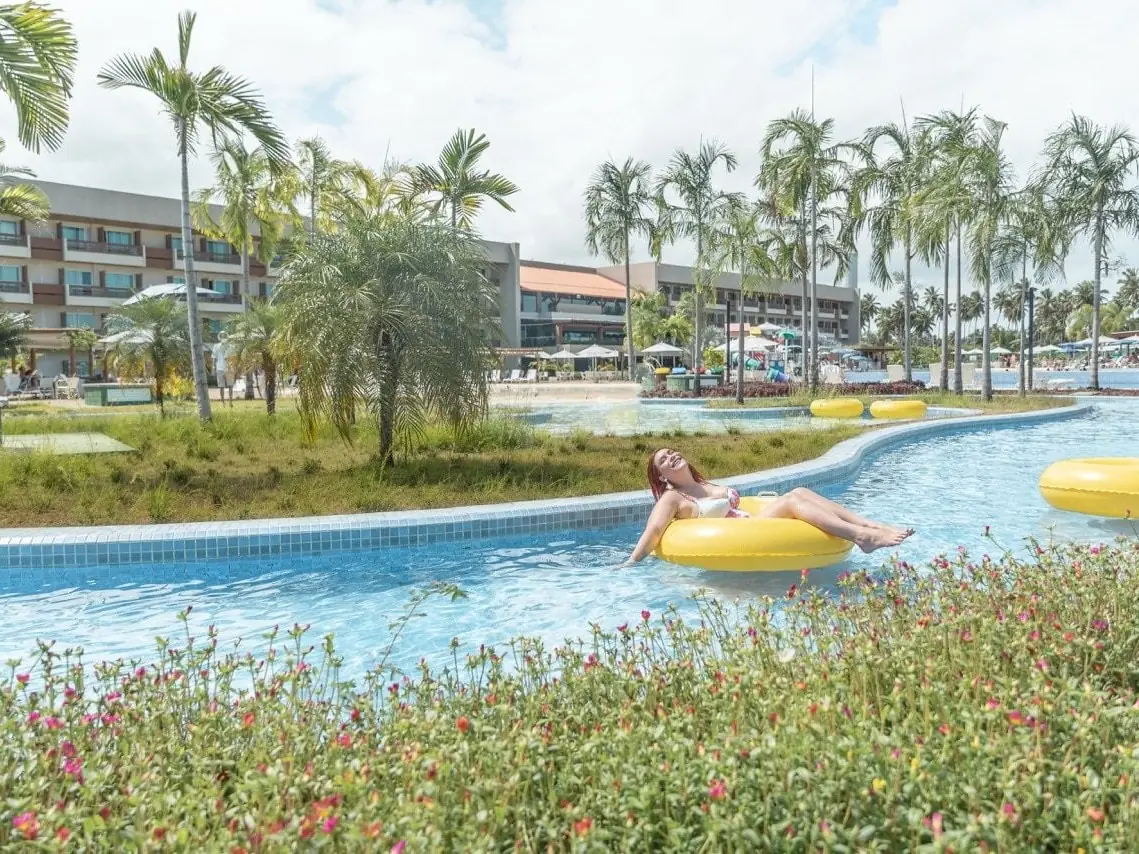 Hóspede numa boia amarela na piscina de correnteza do Japaratinga Lounge Resort, com os blocos ao fundo