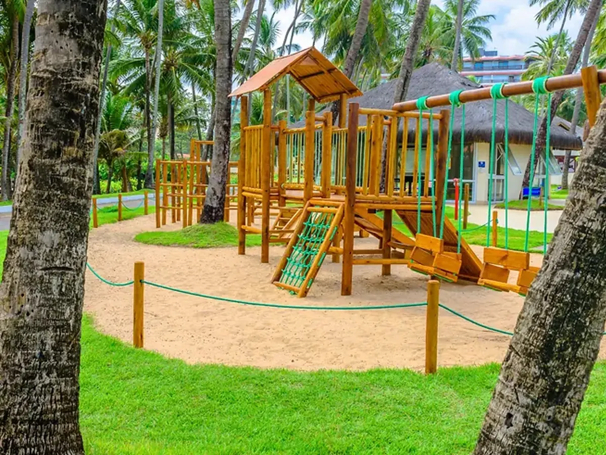 Playground de madeira do Clubinho do Jacaré, na areia, entre coqueiros