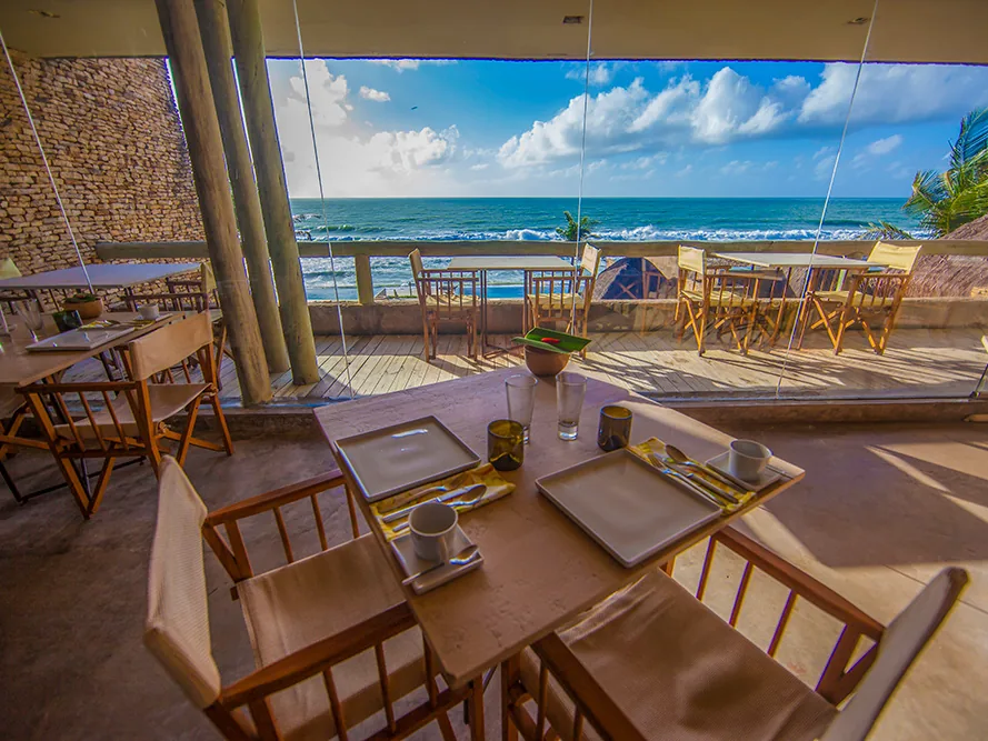 Varanda de refeições do Kenoa Resort, com mesas e cadeiras e o mar ao fundo