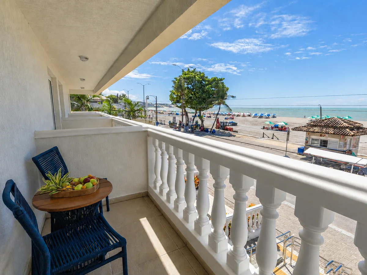 Varanda de um apartamento do SERHS Beach Hotel com mesa e cadeiras, de frente para o calçadão e a praia de Ponta Negra