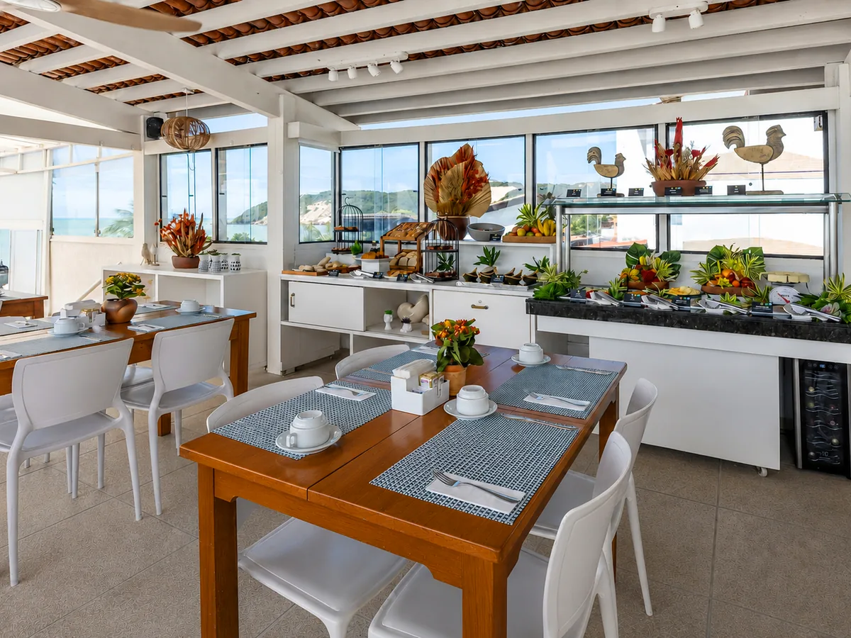 Salão do Veleiro Restaurante & Bar, no SERHS Beach Hotel, com mesas postas, o bufê e janelas para o mar