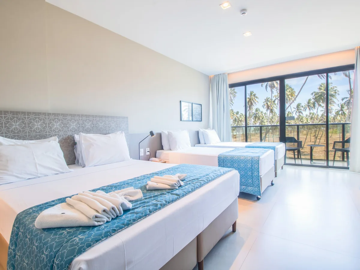 Apartamento Superior do Maceió Mar Resort, com camas para a família e a varanda voltada para o coqueiral