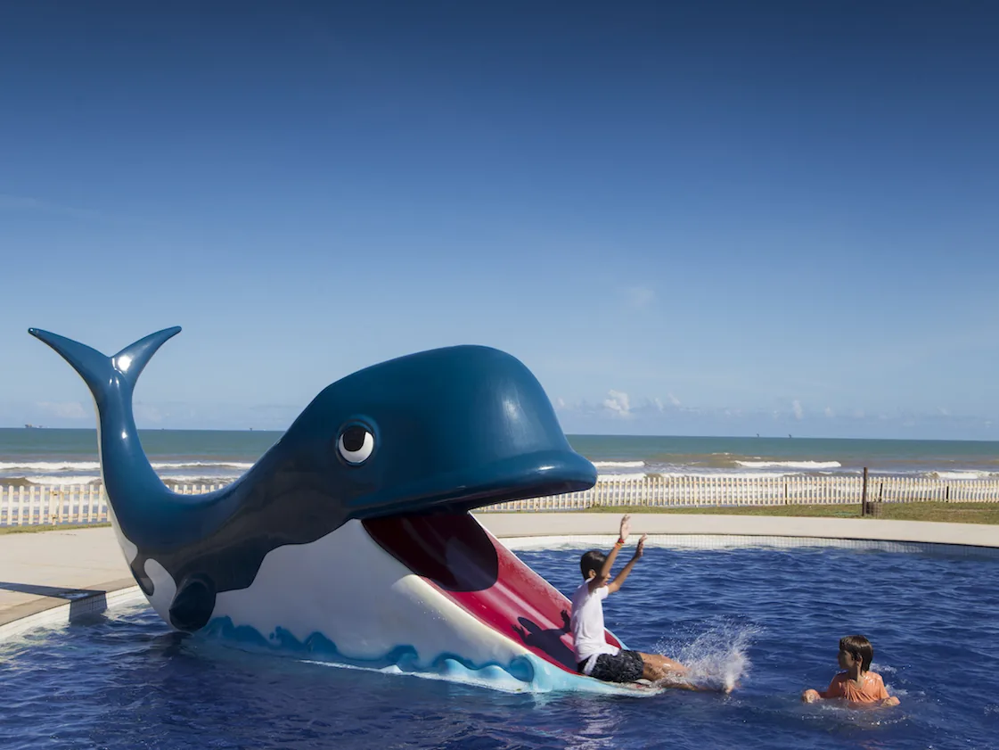 Crianças brincando no escorregador em forma de baleia da piscina infantil do Makai Resort