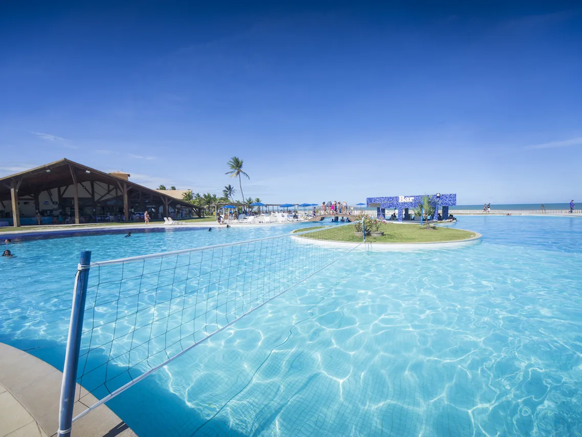 Piscina principal do Makai Resort com uma ilha gramada no meio e rede de vôlei