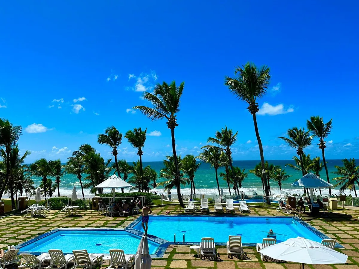 Piscinas do Marsol Beach Resort com espreguiçadeiras e coqueiros, com o mar logo atrás