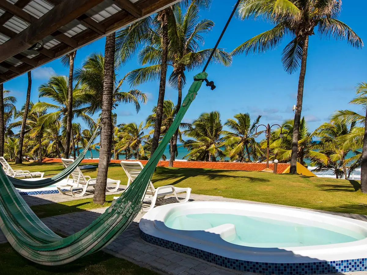 Rede na varanda e jacuzzi em frente a um apartamento do Marsol Beach Resort, com coqueiros e o mar ao fundo