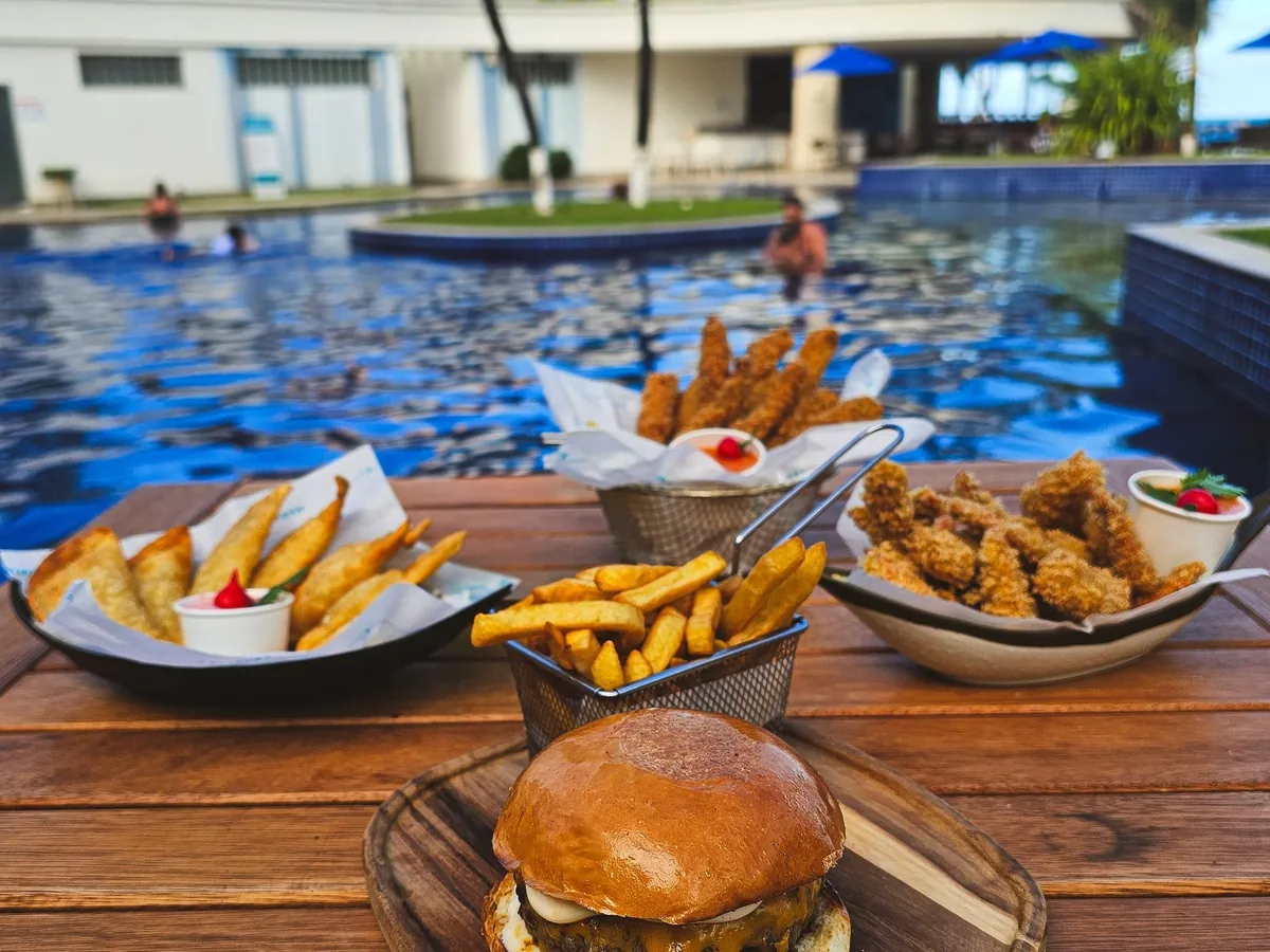 Hambúrguer e batatas fritas servidos à beira da piscina do Marupiara Resort