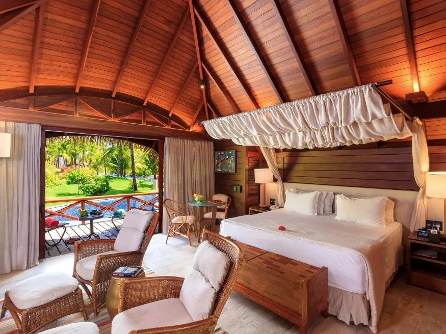 Quarto de um bangalô do NANNAI Muro Alto, com cama de dossel e portas abertas para o jardim