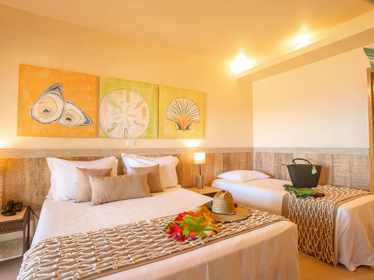 Apartamento do Ocaporã Hotel com cama de casal, cama de solteiro e quadros de conchas na parede
