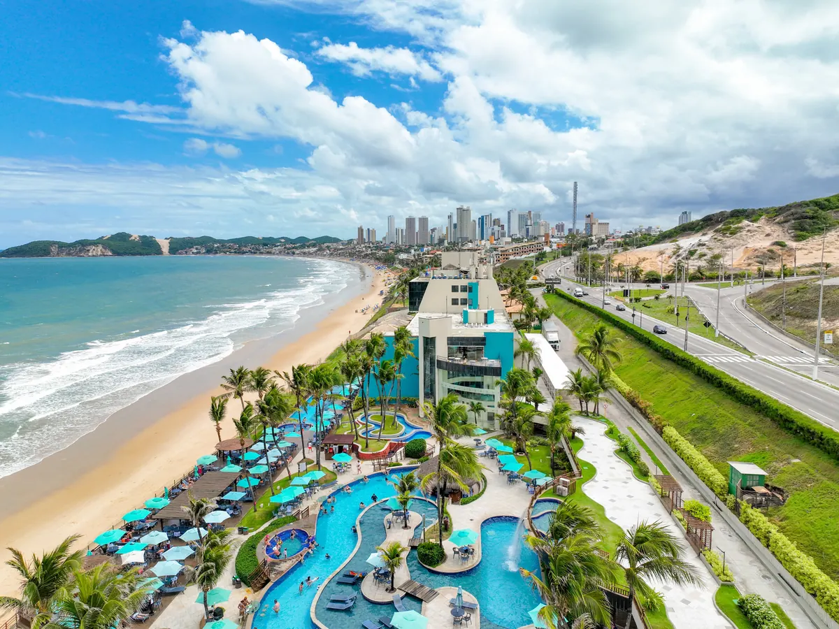 Vista aérea do Ocean Palace, com as piscinas, a Via Costeira ao lado e a praia de Ponta Negra ao fundo