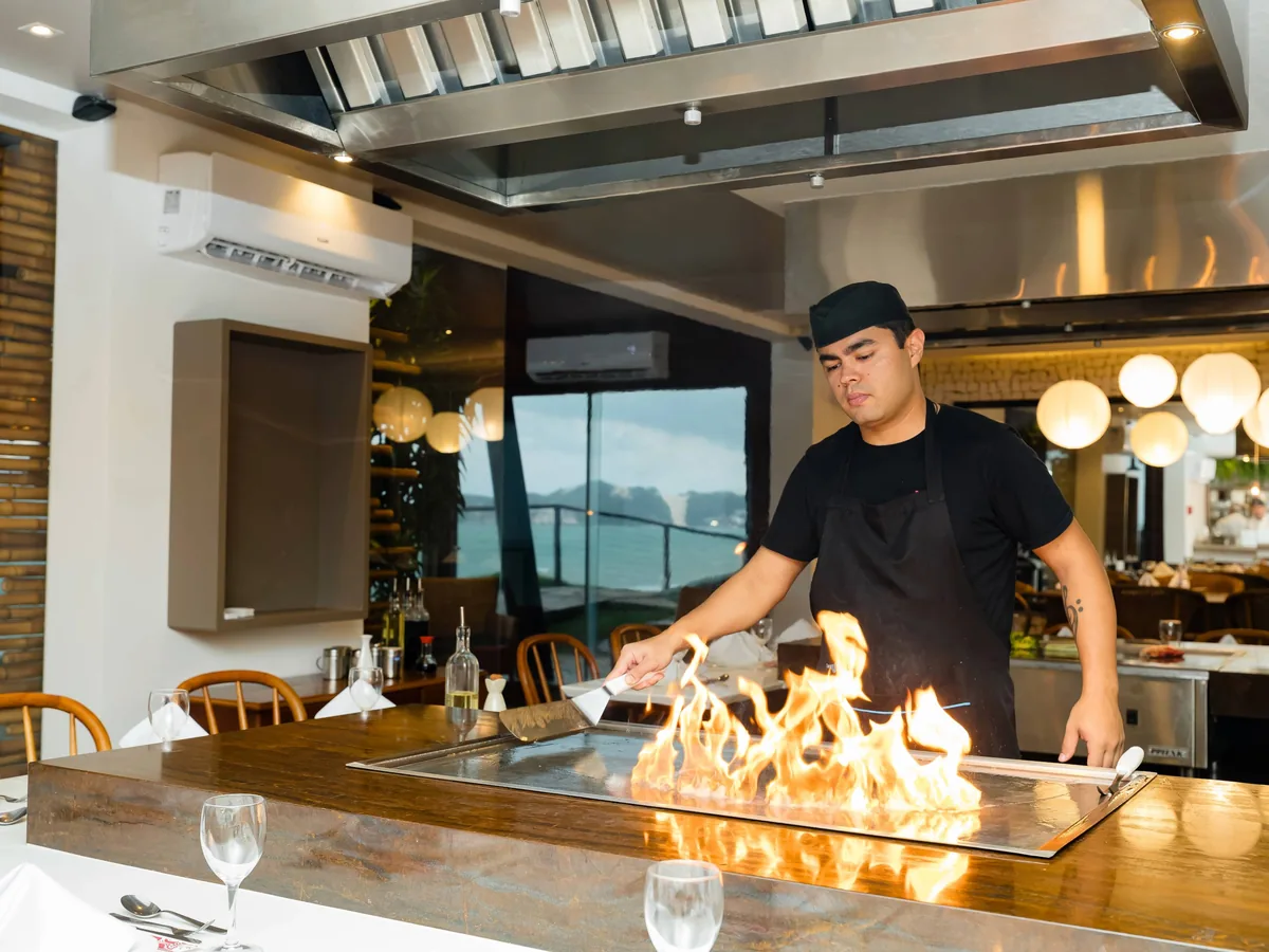 Chef preparando comida na chapa de teppanyaki, com chamas, em um restaurante do Ocean Palace