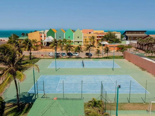 Quadras de tênis do Oceani Beach Park vistas do alto, com os prédios coloridos e o mar ao fundo