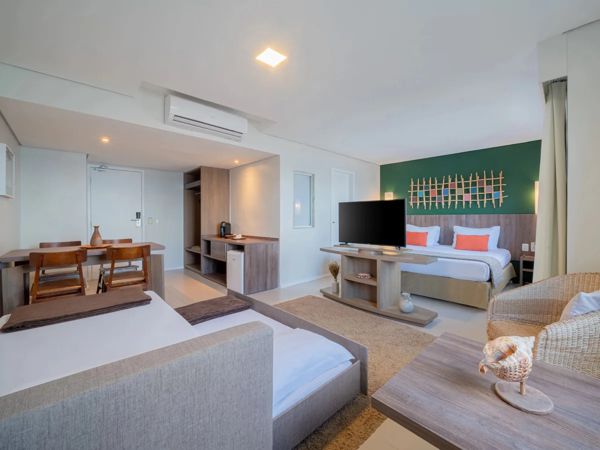 Suíte Master do Oceani Beach Park, com cama de casal, sofá-cama, TV e mesa