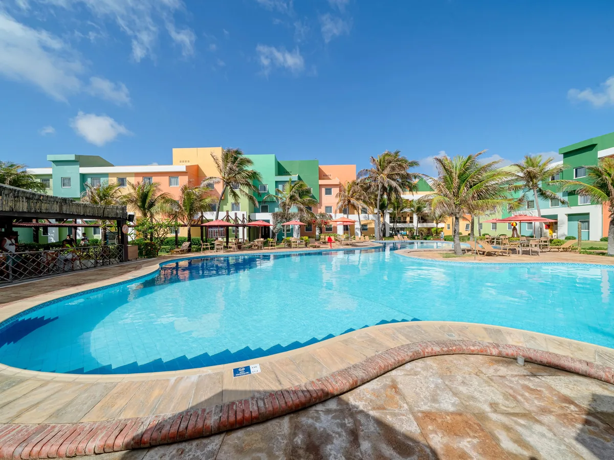 Piscina do Oceani Beach Park com os prédios coloridos do resort ao fundo, entre coqueiros