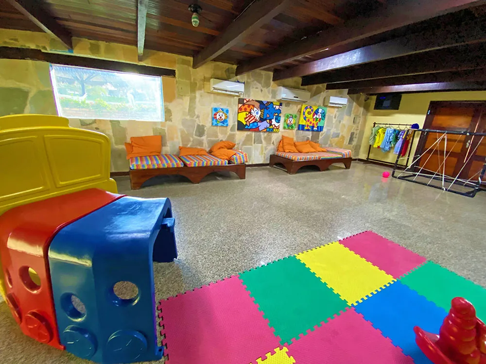 Sala do Kids Club do Hotel Parque das Fontes, com tapete de encaixe colorido, brinquedos e quadros infantis nas paredes