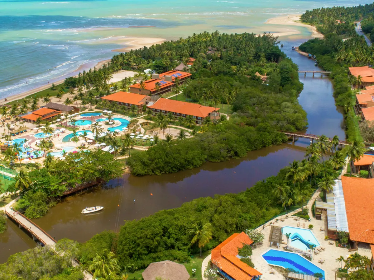 Vista aérea do Salinas Maragogi, com o Rio Maragogi, os blocos de telhado laranja, as piscinas e o mar