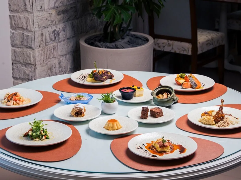 Mesa redonda posta com carnes, peixe, massas e sobremesas no restaurante Tempero