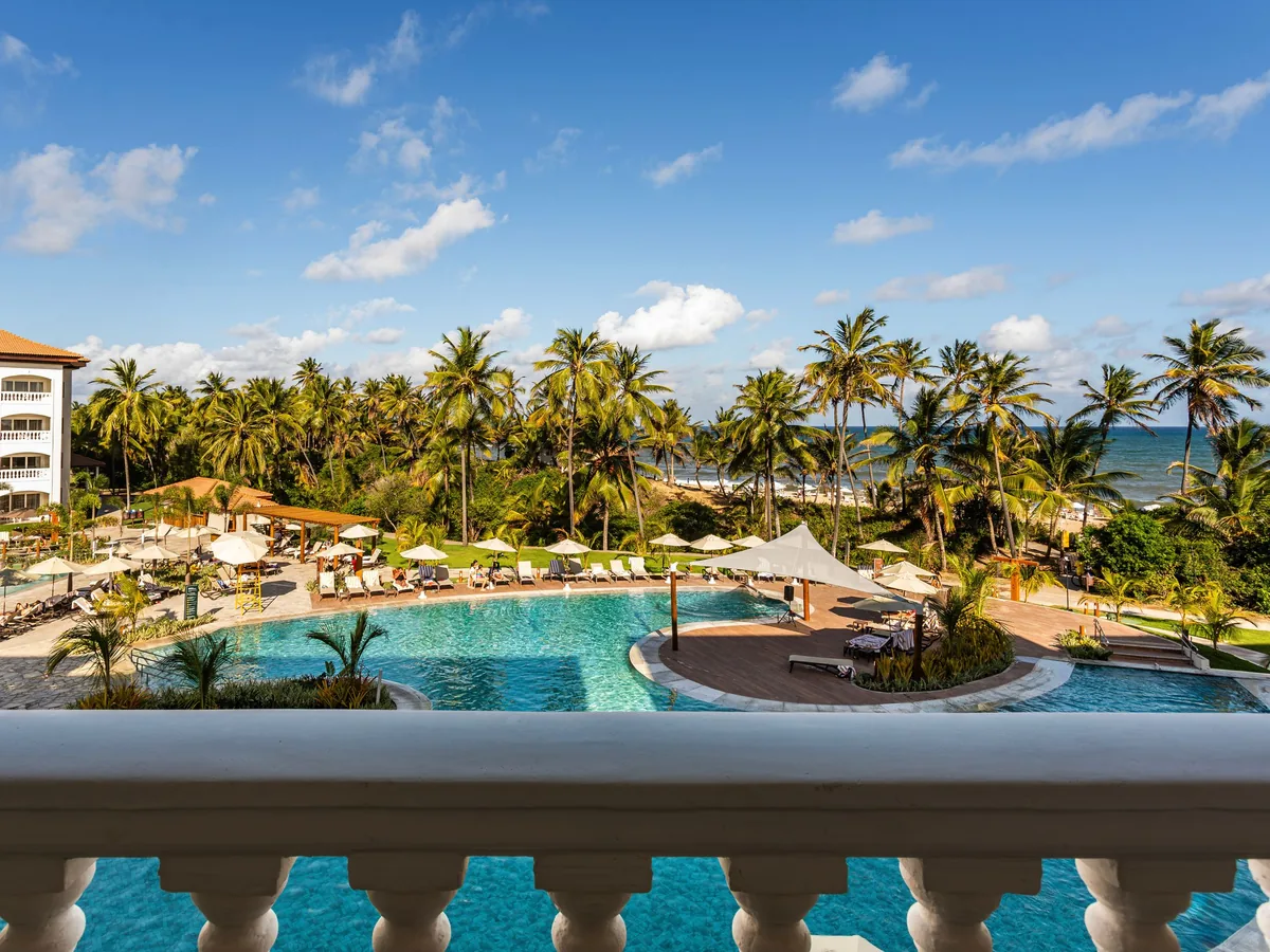 Piscina do Sauípe Sol Grand Premium vista da varanda de um apartamento, com coqueiros e o mar ao fundo