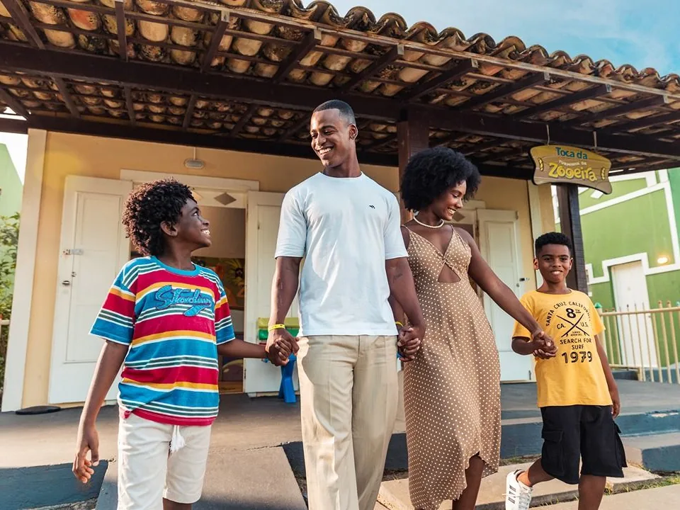 Família de mãos dadas saindo da Toca da Zooeira, o clube infantil da Costa do Sauípe