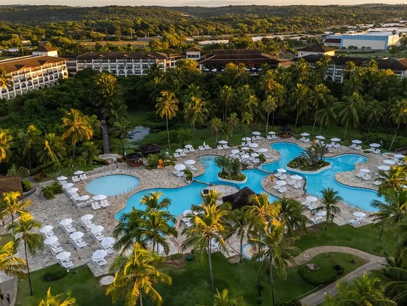 Piscinas do Sauípe Terra Resort vistas do alto ao entardecer, cercadas de coqueiros e guarda-sóis