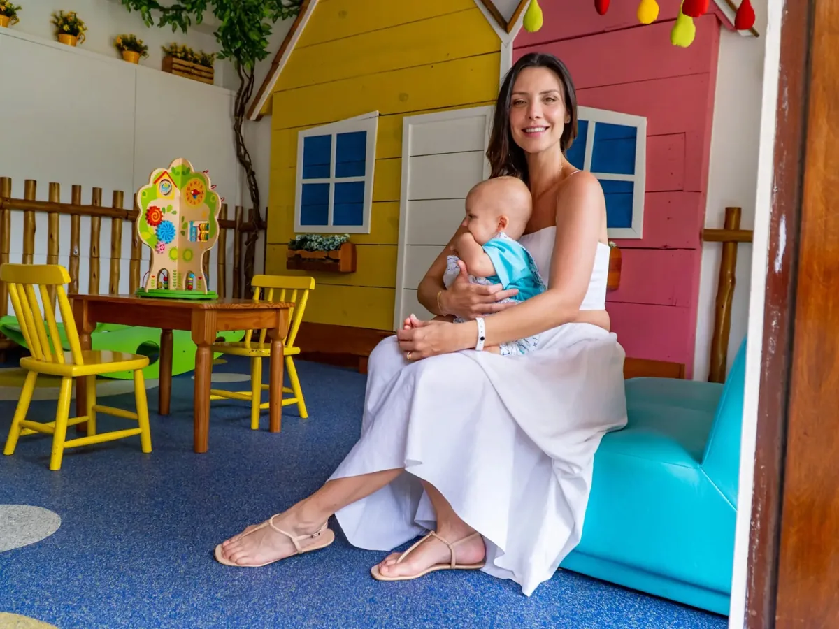 Mãe com o bebê no colo no Baby Club do Summerville, com casinha colorida e cadeirinhas