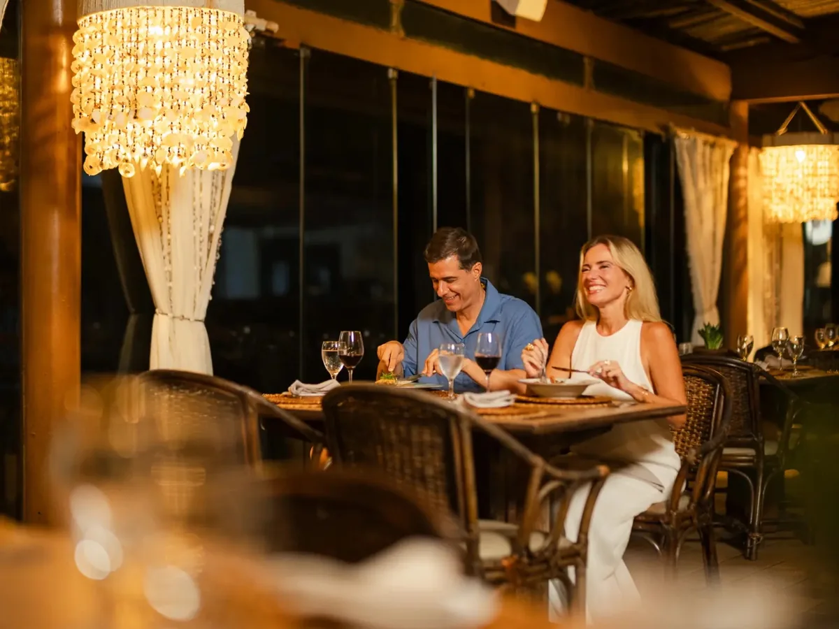 Casal jantando no restaurante Quebramar do Summerville, com lustres e cortinas