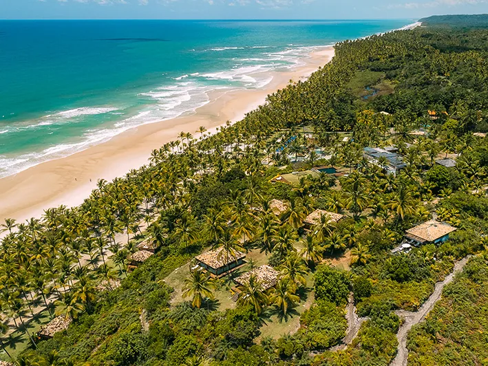 Vista aérea do Txai, com os bangalôs entre os coqueiros, a praia de Itacarezinho e o mar