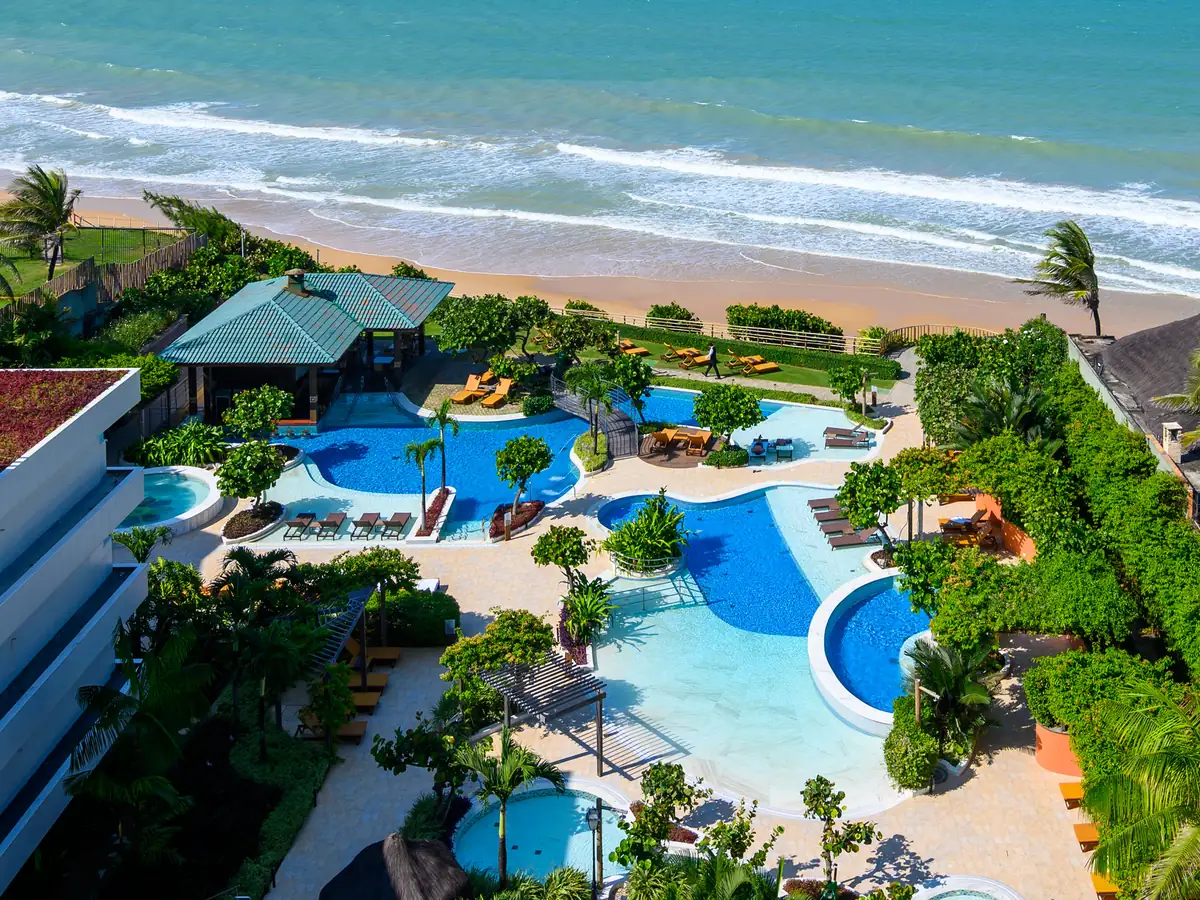 O Vogal Luxury Beach Hotel visto do alto, com as piscinas, o gramado e a praia de Ponta Negra logo depois