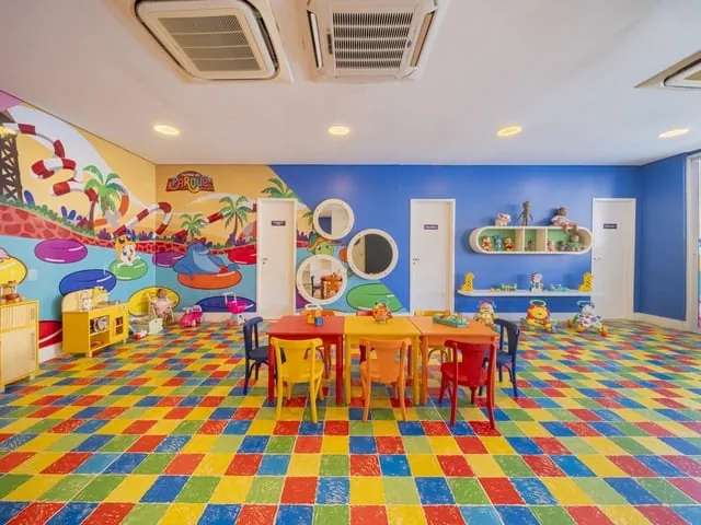 Espaço kids do Wellness Beach Park, com mesas infantis, piso colorido e parede pintada