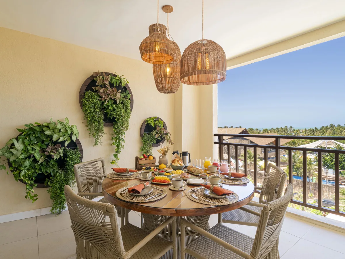 Varanda de uma suíte do Wellness Beach Park, com mesa de café da manhã posta e vista para os coqueiros