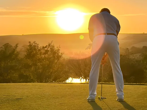 Golfista no campo do Aguativa ao pôr do sol